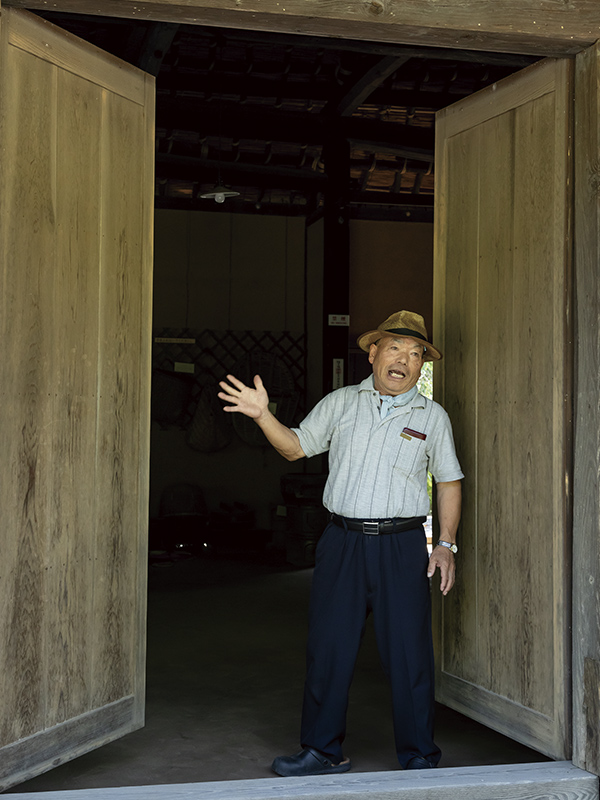 滝沢屋の観音開きの大扉を説明するガイドの木村富夫さん。
